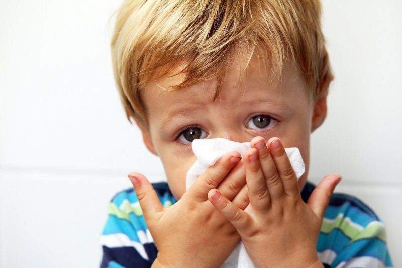 kid blowing nose because of allergies